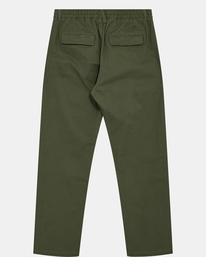 Vista posteriore flat lay dei pantaloni Anerkjendt AKJAN Cotton Pleat Ela Pants in Khaki Sand su sfondo grigio chiaro: retro dei pantaloni uomo cotone beige sabbia con vita elastica due tasche posteriori con pattina patch etichetta metallica Anerkjendt e gamba tapered