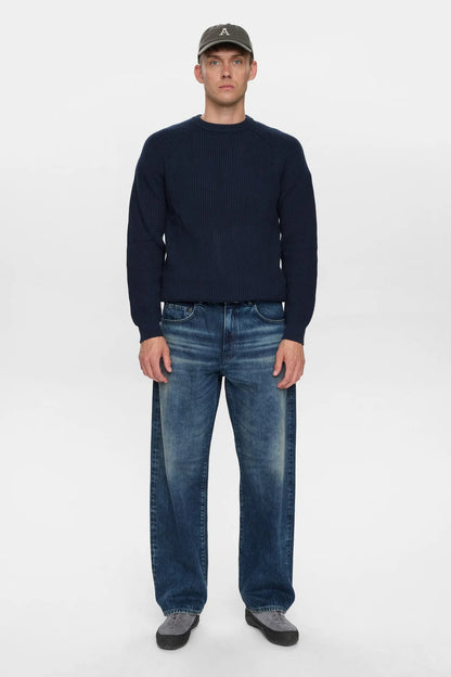 Dettaglio frontale ravvicinato del petto del maglione Anerkjendt AKSUNE Patent Knit Navy Blue indossato dal modello: zoom sulla texture a costine verticali fitte tono su tono e sul collo rotondo ribbed