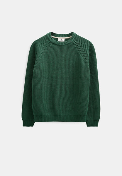 Modello maschile con cappellino verde oliva indossa il maglione Anerkjendt AKSUNE Patent Knit rosso bordeaux con pantaloni neri wide-leg e sneaker grigie: vista frontale intera testa-piedi su sfondo bianco che mostra il fit regular del maglione a costine