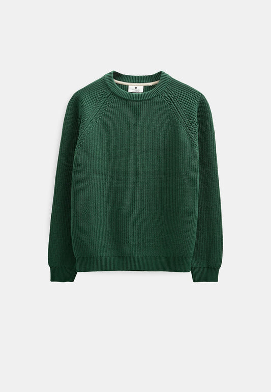 Modello maschile con cappellino verde oliva indossa il maglione Anerkjendt AKSUNE Patent Knit rosso bordeaux con pantaloni neri wide-leg e sneaker grigie: vista frontale intera testa-piedi su sfondo bianco che mostra il fit regular del maglione a costine