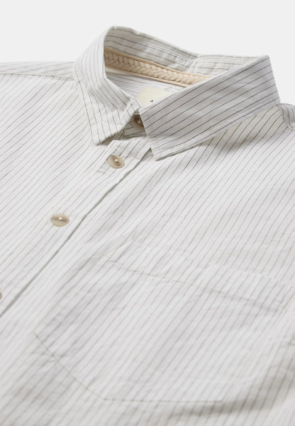 Modello maschile con cappellino nero indossa la Anerkjendt AKOTTO Poplin Stripe LS Shirt Bright White con jeans wide-leg lavaggio medio e sneaker grigie: vista frontale intera con camicia a righe sottili grigio-blu colletto button-down e tasca a toppa sul petto
