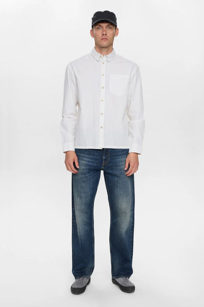Dettaglio ravvicinato del colletto button-down e della tasca a toppa sul petto della Anerkjendt AKOTTO Poplin Stripe LS Shirt Bright White: primo piano dei bottoni perlati tonali bianchi e del tessuto popeline a righe sottili grigio-blu su fondo bianco avorio