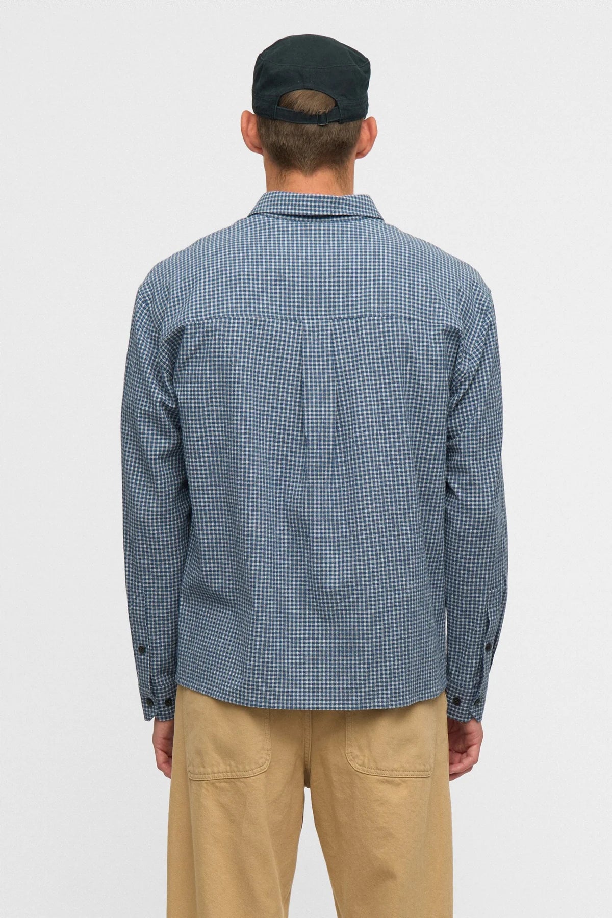 Vista posteriore flat lay della Anerkjendt AKOTTO Small Check LS Shirt Estate Blue: retro della camicia uomo a micro quadri blu navy e bianco con yoke posteriore piega centrale e polsini a doppio bottone scuro su sfondo grigio chiaro