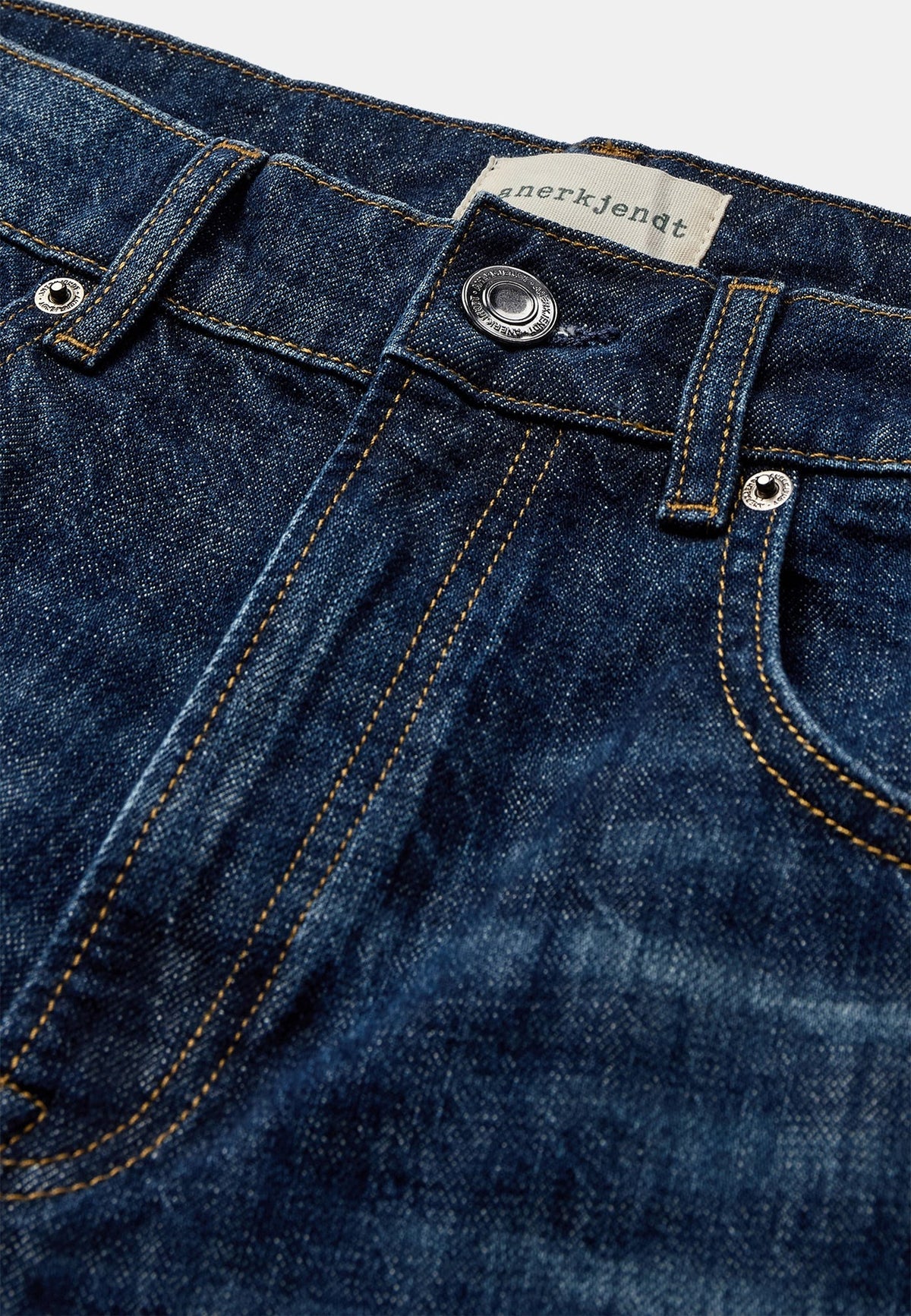 Vista frontale ravvicinata dei jeans Anerkjendt AKJUSTIN 8016 Dark Blue Sky indossati dal modello: zoom su vita e cosce con denim blu medio lavaggio vintage, texture jacquard all-over con pattern lettera A in rilievo, cintura con passanti e chiusura a bottone metallico argento